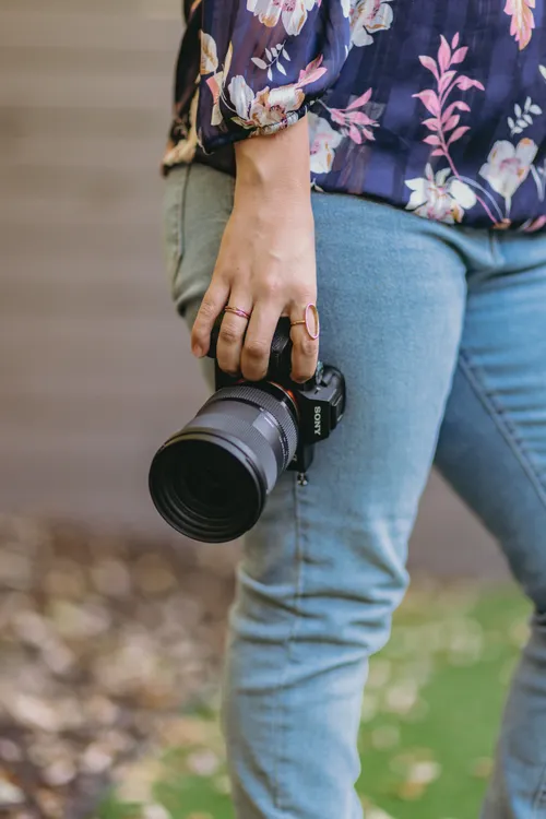 Close-up of Luisa's hands holding her Sony camera with delicate rings, capturing the craft and care she brings to photography