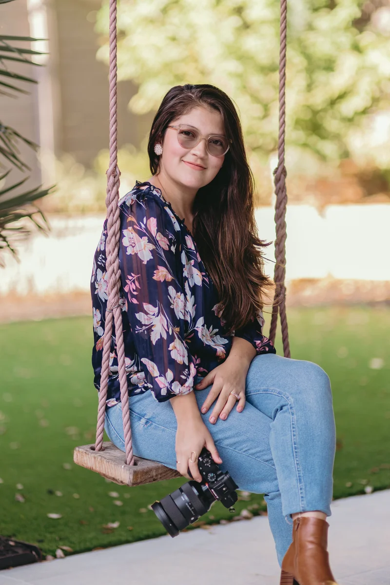 Luisa sitting on a rope swing outdoors, smiling naturally in a lush green garden